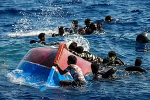 Migrantes nadan junto a su bote de madera volcado durante una operación de rescate de la ONG española Open Arms al sur de la isla italiana de Lampedusa en el mar Mediterráneo, el jueves 11 de agosto de 2022. Foto AP/Francisco Seco