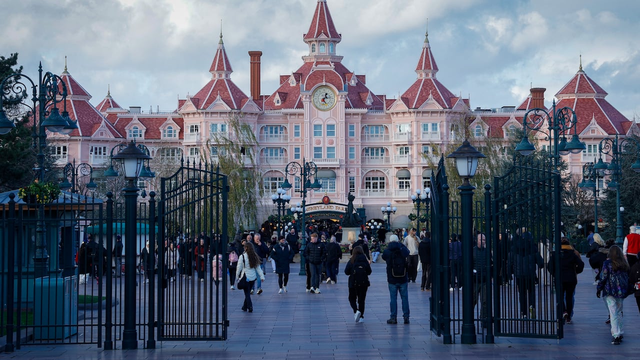 Esta fotografía, tomada el 24 de noviembre de 2025, muestra a los visitantes frente al Hotel Disneyland, que marca la entrada al Parque Disneyland en Disneyland París, en Marne-la-Vallée, al este de París. (Foto de GEOFFROY VAN DER HASSELT / AFP)