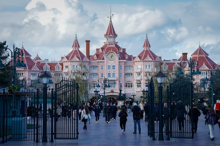 Esta fotografía, tomada el 24 de noviembre de 2025, muestra a los visitantes frente al Hotel Disneyland, que marca la entrada al Parque Disneyland en Disneyland París, en Marne-la-Vallée, al este de París. (Foto de GEOFFROY VAN DER HASSELT / AFP)