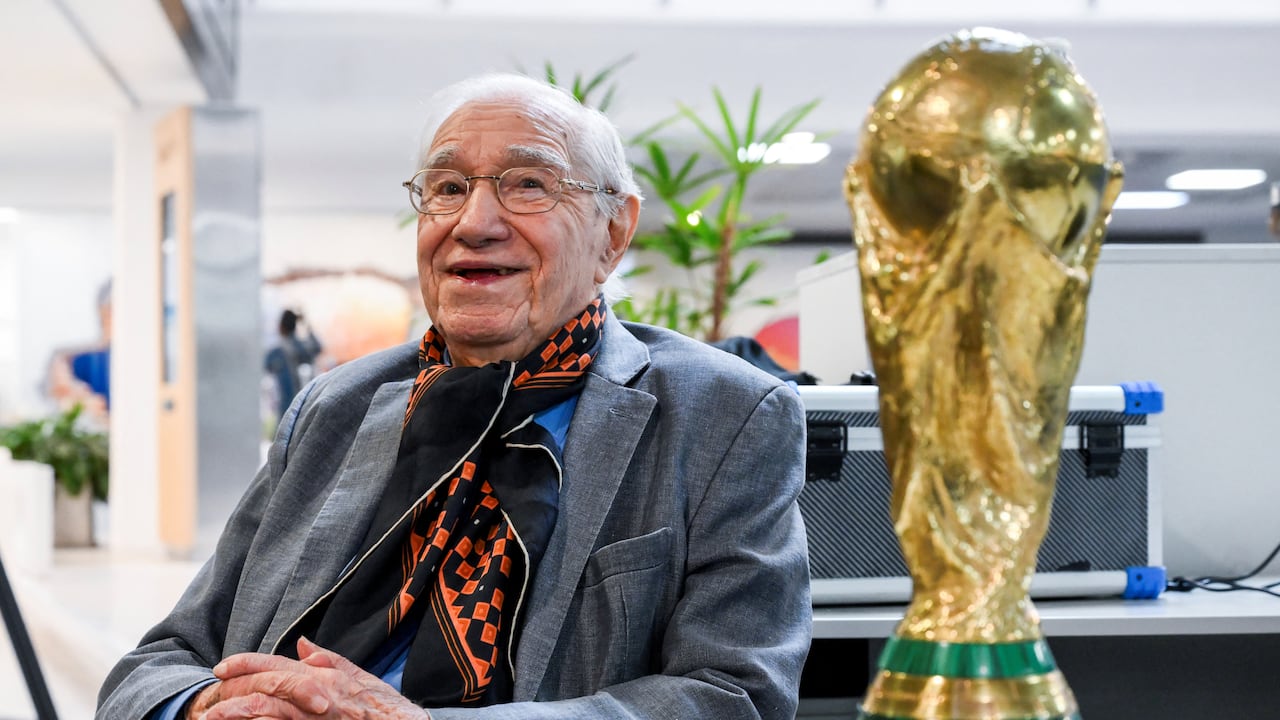 El periodista deportivo y analista de fútbol argentino Enrique Macaya Márquez, de 91 años, posa para una foto con una réplica del trofeo de la Copa Mundial de la FIFA. Desde Suecia 1958, el fútbol ha cambiado en términos tácticos, tecnológicos y económicos. Sin embargo, algo se ha mantenido constante: la presencia del periodista argentino Enrique Macaya Márquez, quien extenderá su récord de cobertura de la Copa Mundial a 18 en Norteamérica 2026. (Foto de Luis ROBAYO / AFP)