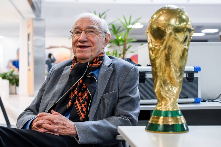El periodista deportivo y analista de fútbol argentino Enrique Macaya Márquez, de 91 años, posa para una foto con una réplica del trofeo de la Copa Mundial de la FIFA. Desde Suecia 1958, el fútbol ha cambiado en términos tácticos, tecnológicos y económicos. Sin embargo, algo se ha mantenido constante: la presencia del periodista argentino Enrique Macaya Márquez, quien extenderá su récord de cobertura de la Copa Mundial a 18 en Norteamérica 2026. (Foto de Luis ROBAYO / AFP)