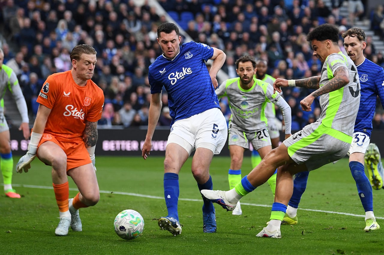 El centrocampista irlandés del Manchester City, Nico O'Reilly (derecha), número 33, dispara a puerta frente al portero inglés del Everton, Jordan Pickford (izquierda), número 1, durante el partido de la Premier League entre el Everton y el Manchester City en el estadio Hill Dickinson de Liverpool el 4 de mayo de 2026. (Foto de PETER POWELL / AFP)