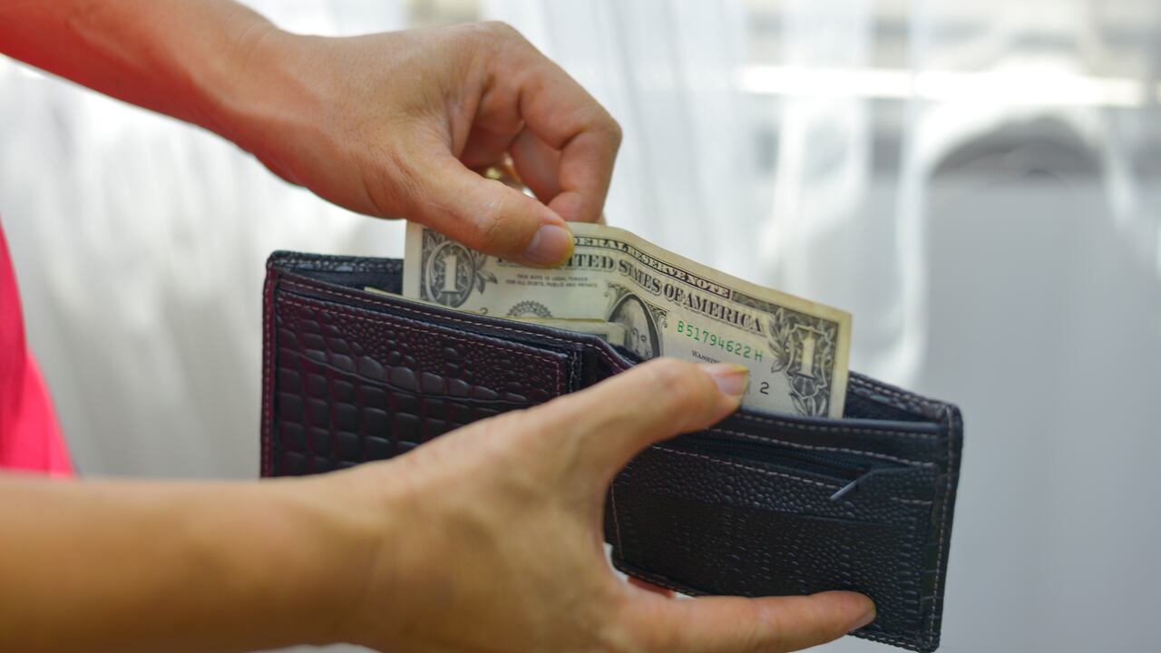 The young man is opening his wallet to pick up money from his wallet.