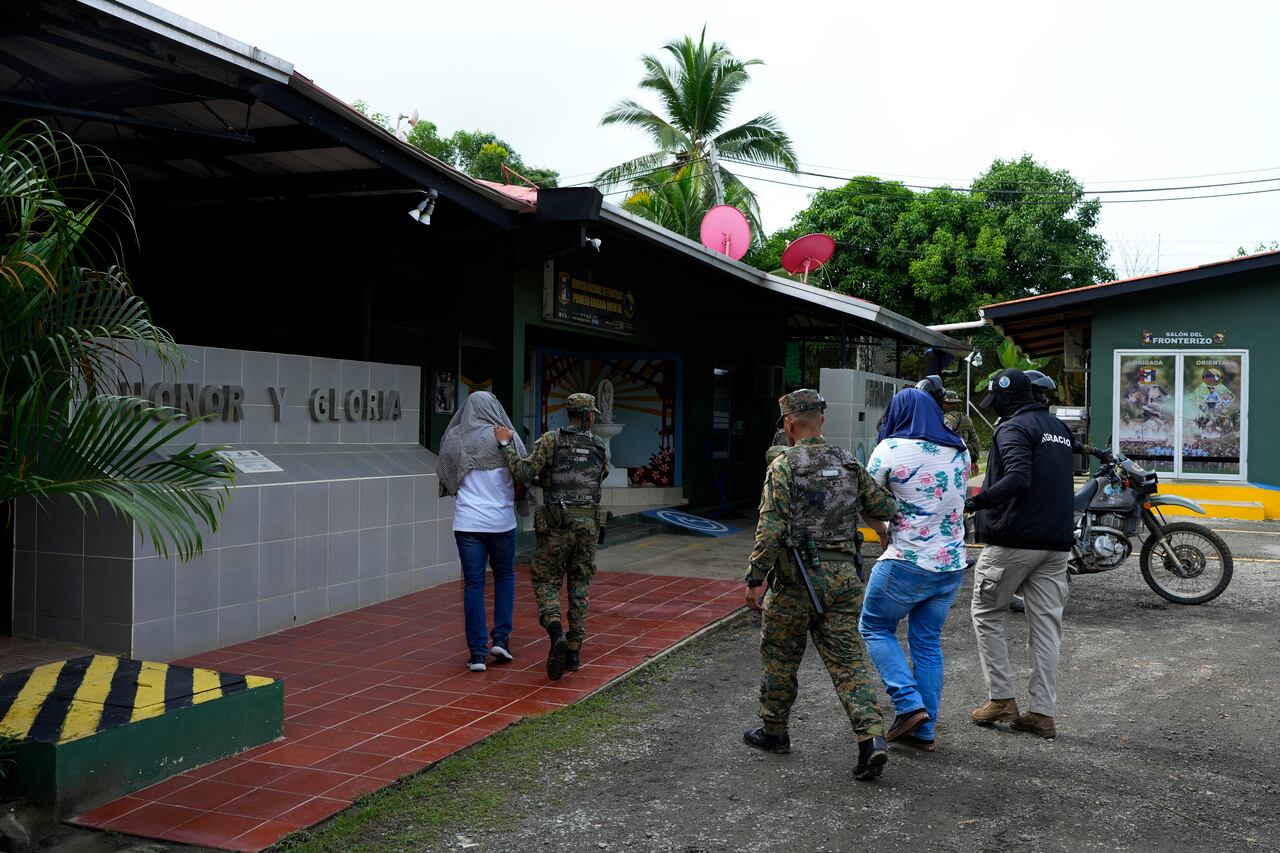 Oficiales de la policía fronteriza panameña detienen a dos hombres durante una operación contra el tráfico de migrantes.