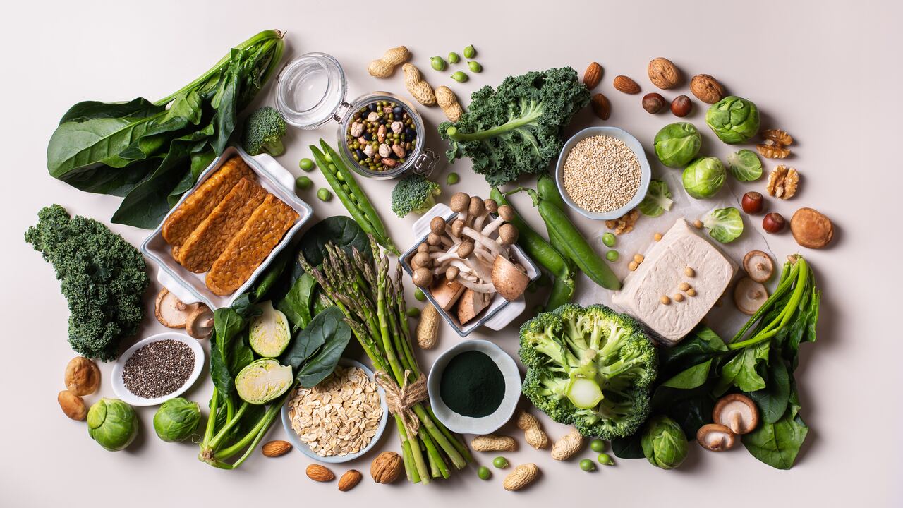 Variedad de alimentos veganos saludables, fuentes de proteínas a base de plantas y alimentos para la construcción del cuerpo. Tofu soja tempeh, vegetales verdes, nueces, semillas, harina de avena con quinua y espirulina. Vista desde arriba