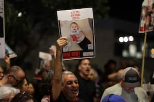 A man raises a portrait of Kfir Bibas, as relatives and supporters of Israeli hostages held in Gaza since the October 7 attacks by Hamas in southern Israel, take part in a rally calling for their release, outside the PM's office in Jerusalem on May 22, 2024. (Photo by AHMAD GHARABLI / AFP)