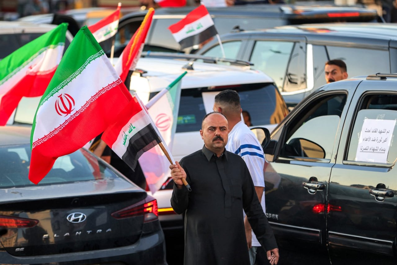 Un hombre sostiene una bandera iraní mientras se desplaza entre vehículos durante las celebraciones por el alto el fuego de dos semanas entre Estados Unidos e Irán en la plaza Tahrir de Bagdad, el 8 de abril de 2026