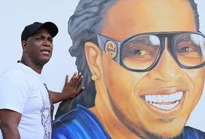 Willy García posa junto a un retrato de Junior Jein, artista bonaverense asesinado este año.