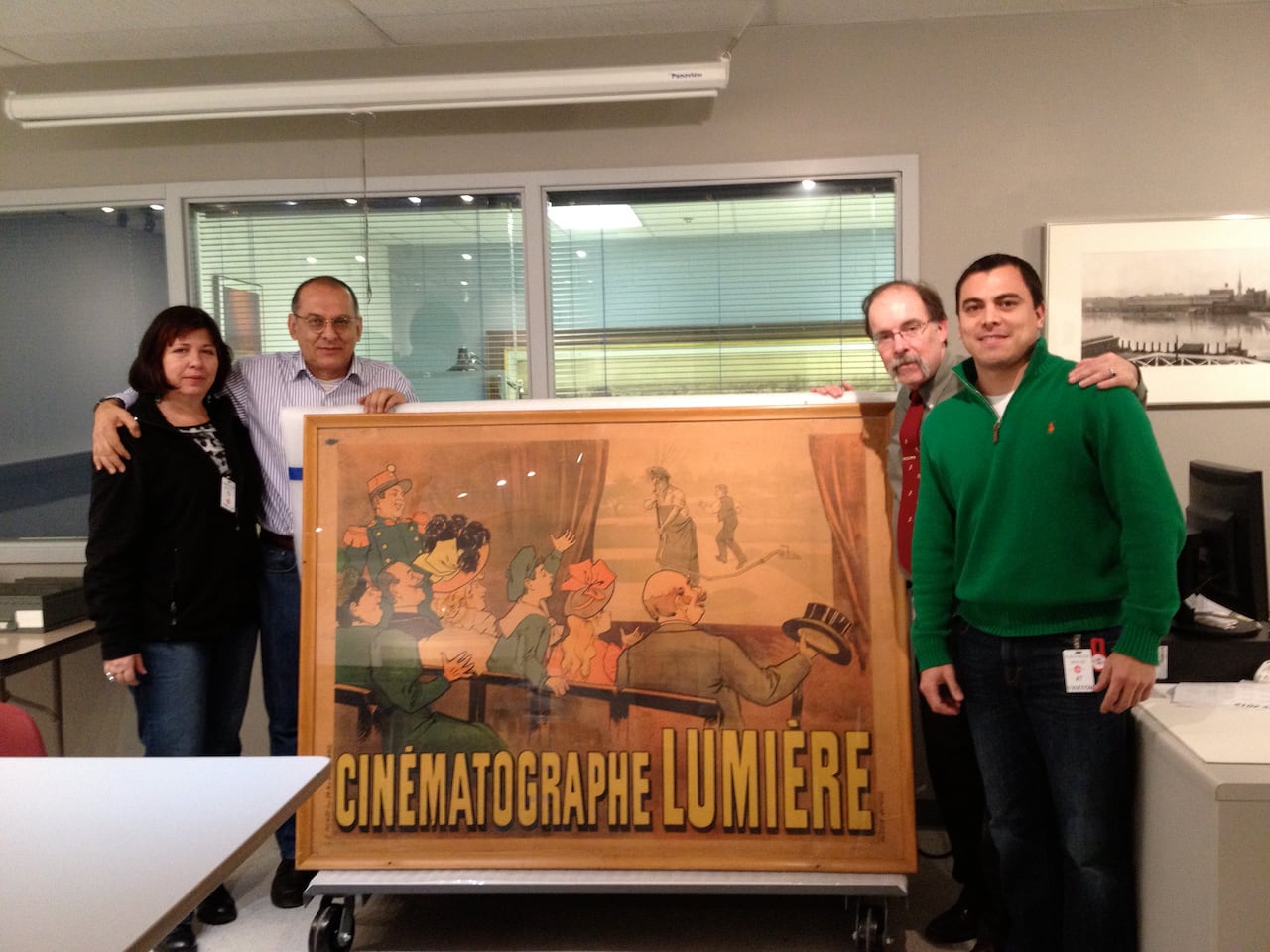 Durante visita al George Eastman House, aparecen Gloria Escobar Lozano, Hugo Suárez Fiat, el curador de la institución americana y Edgardo Zúñiga. Al pie el afiche de “El Regador Regado”.