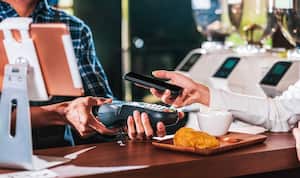 Propietario de una pequeña empresa y puesta en marcha en una cafetería, Primer cliente asiático mano del hombre pagando dinero a través del canal sin contacto mediante la aplicación de banca móvil al propietario de una pequeña empresa en la mesa de la cafetería