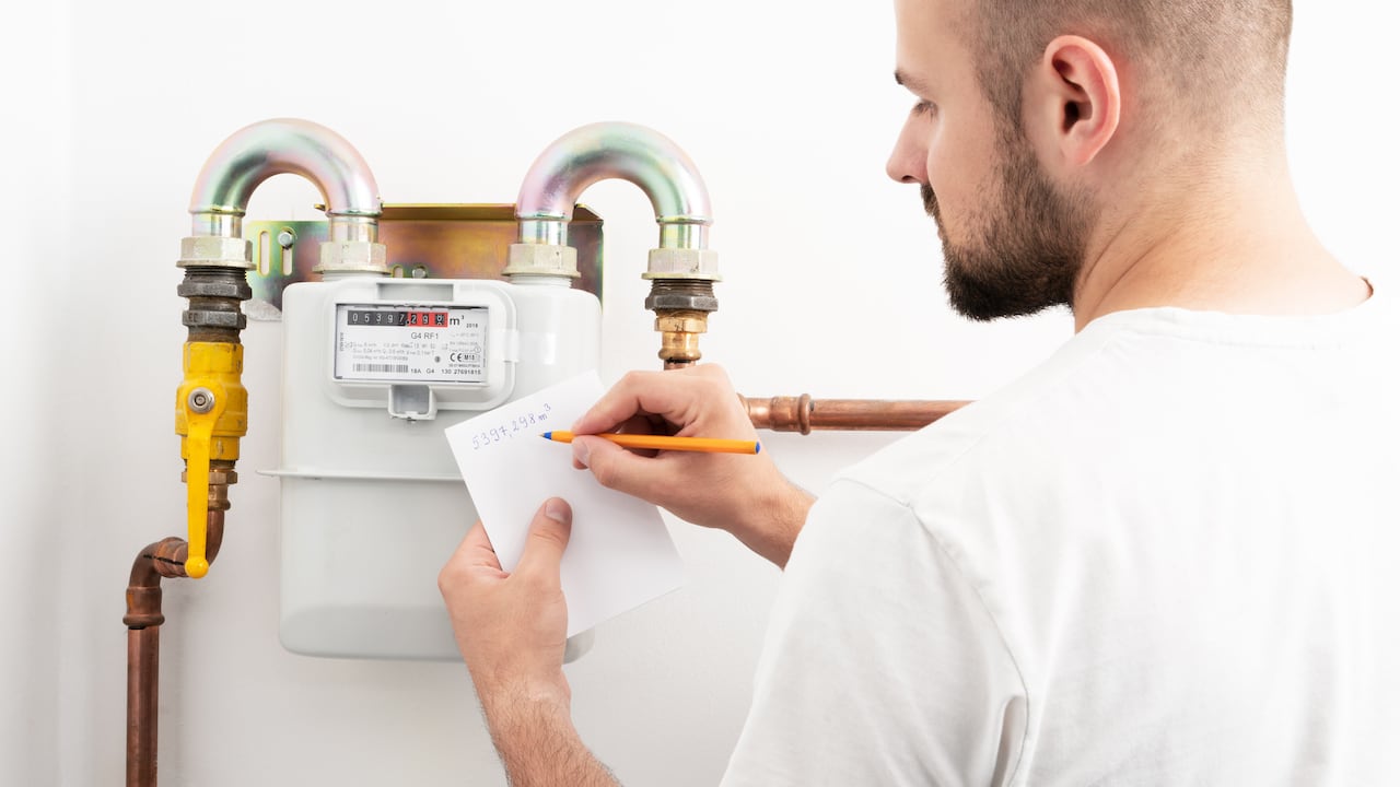 Young man reading the gas meter in the private house, counter for distribution domestic gas.