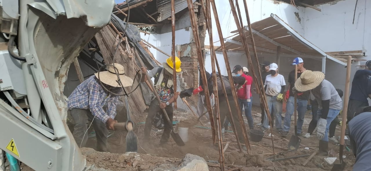 Un grupo de muchachos golpea con porras los muros que quedaron en pie tras el temblor.
