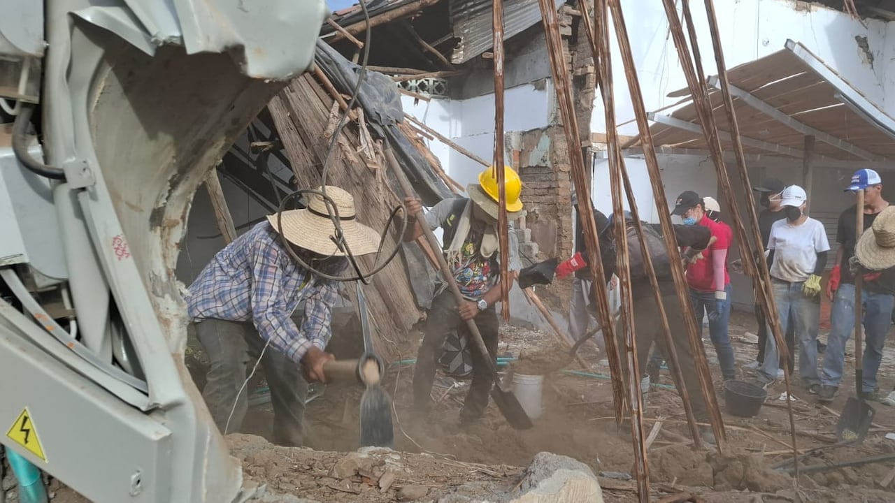 Un grupo de muchachos golpea con porras los muros que quedaron en pie tras el temblor.