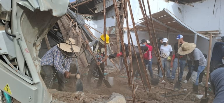 Un grupo de muchachos golpea con porras los muros que quedaron en pie tras el temblor.
