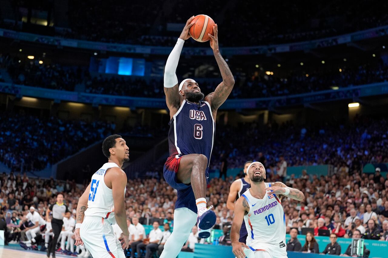 El estadounidense LeBron James (6) se eleva para una volcada en el partido contra Puerto Rico en el baloncesto de los Juegos Olímpicos de París, el sábado 3 de agosto de 2024, en Villeneuve-d'Ascq, Francia. (AP Foto/Michael Conroy)
