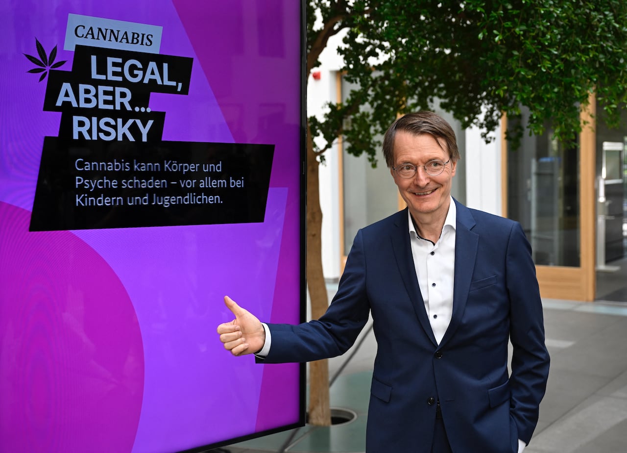 German Health Minister Karl Lauterbach poses next to a campaign placard on legalizing Cannabis, in Berlin on August 16, 2023. The German government approved a draft law on August 16, 2023 legalising the purchase and possession of small amounts of cannabis for recreational use, despite criticism from opposition politicians and judges. (Photo by Tobias SCHWARZ / AFP)