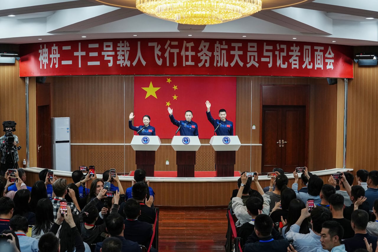 Astronauts for China's Shenzhou-23 space mission Lai Ka-ying (L), Zhu Yangzhu (C) and Zhang Zhiyuan (R) wave during a press conference before the launch of the mission at the Jiuquan Satellite Launch Center in the Gobi desert in Jiuquan, in northwestern China's Gansu province on May 23, 2026. (Photo by CNS / AFP) / China OUT