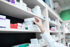 Closeup view of pharmacist hand taking medicine box from the shelf in drug store.