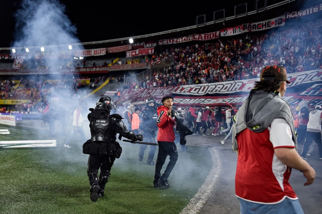 Momento en el que las unidades de seguridad retiran del campo de juego a los hinchas de Santa Fe tras los enfrentamiento con la barra del América.