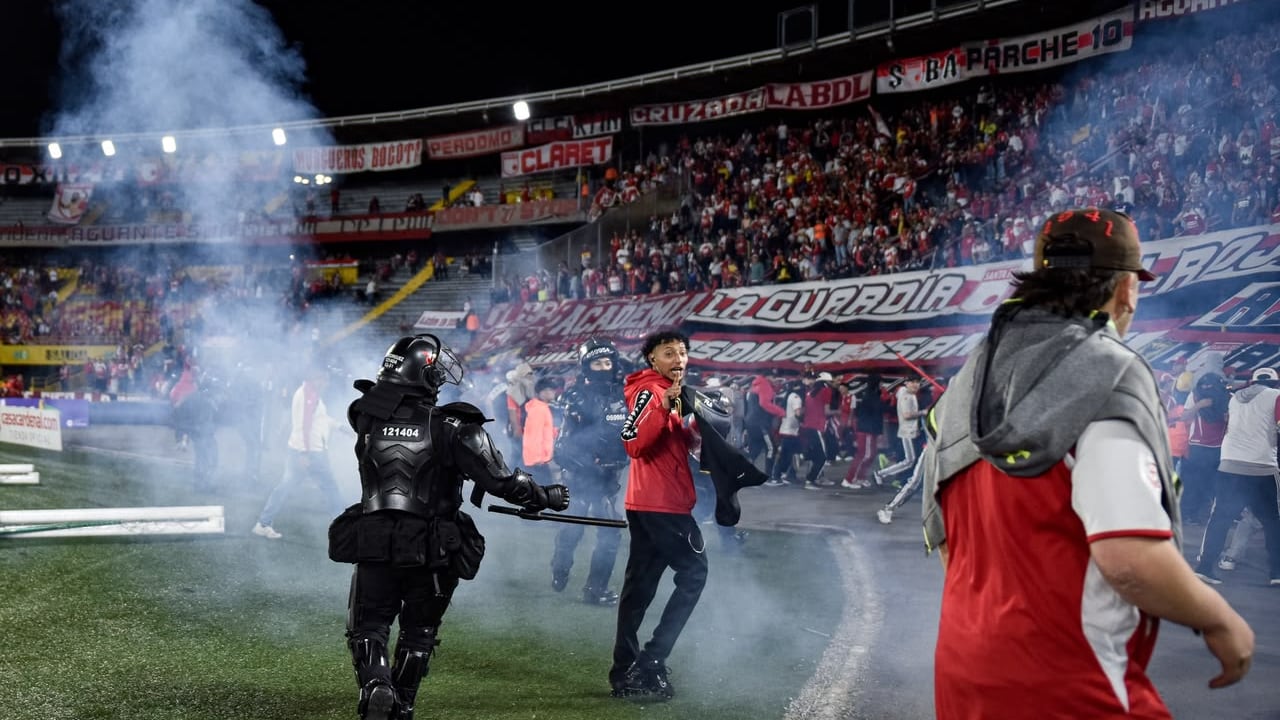 Momento en el que las unidades de seguridad retiran del campo de juego a los hinchas de Santa Fe tras los enfrentamiento con la barra del América.