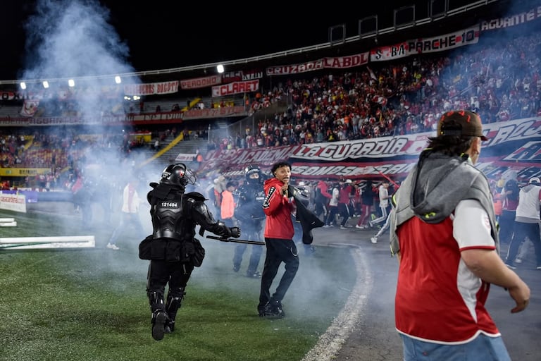 Momento en el que las unidades de seguridad retiran del campo de juego a los hinchas de Santa Fe tras los enfrentamiento con la barra del América.