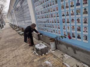 Familiares de personas fallecidas visitan un muro donde están sus fotografías expuestas.