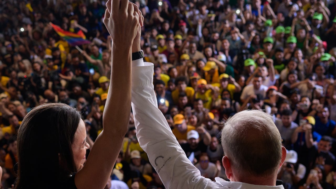 El candidato presidencial venezolano Edmundo González (R) y la líder de la oposición venezolana María Corina Machado saludan a estudiantes durante un mitin de campaña en la Universidad Central de Venezuela en Caracas el 14 de julio de 2024. (Foto de Gabriela Oraa / AFP)