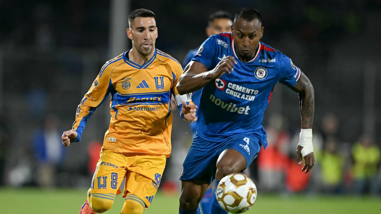 El mediocampista uruguayo de Tigres #08 Fernando Gorriarán (izq.) y el defensa colombiano de Cruz Azul #04 Willer Ditta disputan el balón durante el partido de ida de las semifinales del Apertura de la Liga MX entre Cruz Azul y Tigres en el Estadio Banorte en la Ciudad de México el 3 de diciembre de 2025. (Foto de CARL DE SOUZA / AFP)