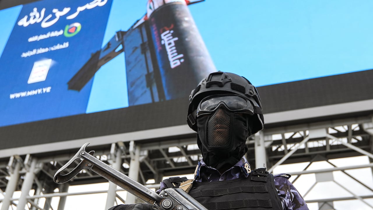 A security personnel officer stands guard in front of a huge image depicting a missile with "Palestine" written on its side, during a rally by supporters of the Iran-backed Houthi movement in solidarity with Iran and Lebanon amid the Middle East war, in the capital Sanaa on April 17, 2026. The Middle East war has created an "unprecedented shock" for the region's economies with no guarantee of a quick recovery, a senior International Monetary Fund official has told AFP. Five of the Gulf's eight oil- and gas-producing countries face a contraction this year, the IMF said in a regional report published on April 16. (Photo by Mohammed HUWAIS / AFP)
