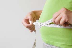 Mujer gorda con sobrepeso midiendo su cintura. Talla extra. Nuevo comienzo para un estilo de vida saludable, adelgazamiento corporal y pérdida de peso. Preocuparse por el cuerpo. Copie el espacio. Lugar vacío para texto sobre fondo gris.