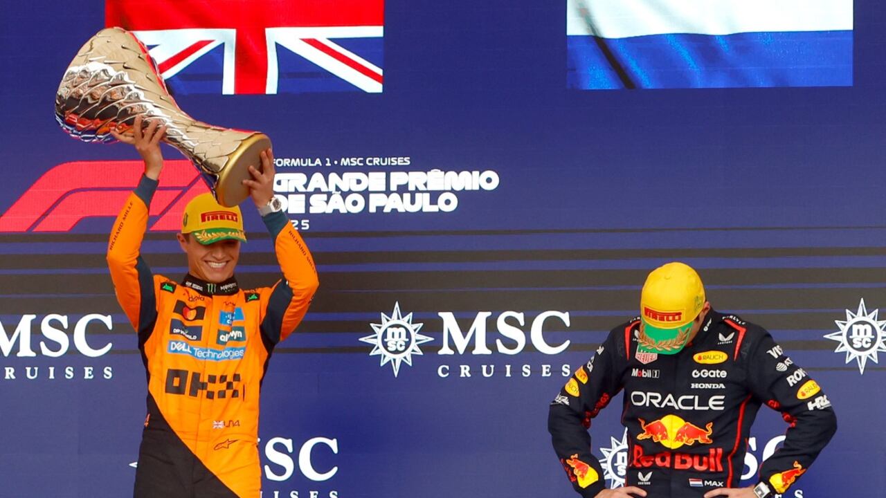 El piloto británico Lando Norris (izq.), ganador del equipo McLaren, levanta el trofeo en el podio pasando junto al piloto holandés Max Verstappen (der.), de Red Bull Racing, que quedó en tercer lugar.