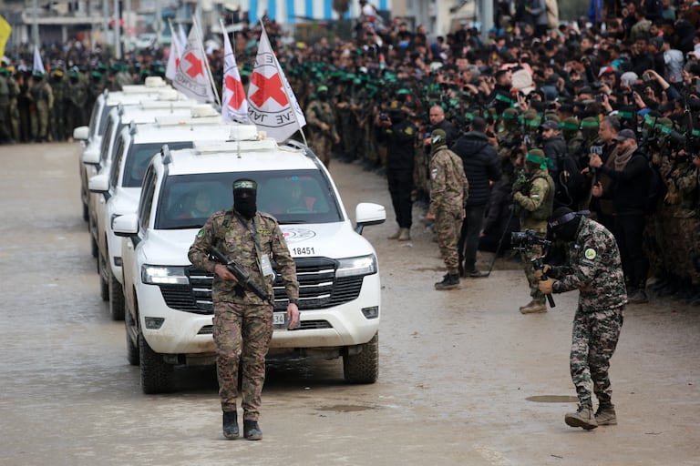 Un combatiente palestino de Hamas precede a los vehículos de la Cruz Roja Internacional (CICR) cuando llegan a Nuseirat, en el centro de la Franja de Gaza, para recibir a tres rehenes israelíes como parte del séptimo intercambio de rehenes-prisioneros el 22 de febrero de 2025. Tres rehenes israelíes más fueron liberados por militantes de Hamas en una ceremonia en el centro de Gaza el 22 de febrero, después de que otros dos fueron liberados en la parte sur del territorio palestino. (Foto de Bashar TALEB / AFP)