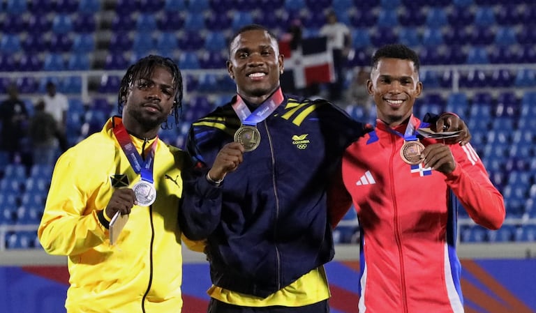 Ronal Longa (centro) al alcanzar la medalla de oro de los 100 metros planos de atletismo de los Juegos Centroamericanos y del Caribe 2026.