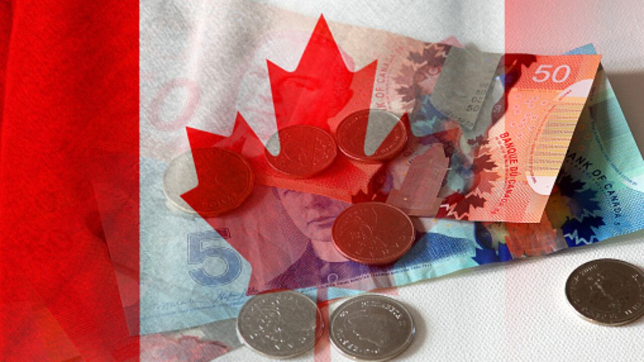 Billetes y monedas en efectivo en dólares canadienses y bandera de Canadá (dinero, economía, negocios, finanzas, inflación, crisis)