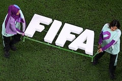 Voluntarios sostienen el logo de la FIFA en un partido internacional.