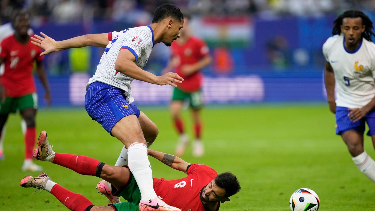 El portugués Bruno Fernandes, en el suelo, intenta enfrentarse a William Saliba de Francia durante un partido de cuartos de final entre Portugal y Francia en el torneo de fútbol Euro 2024 en Hamburgo, Alemania, el viernes 5 de julio de 2024. (Foto AP/Martin Meissner)