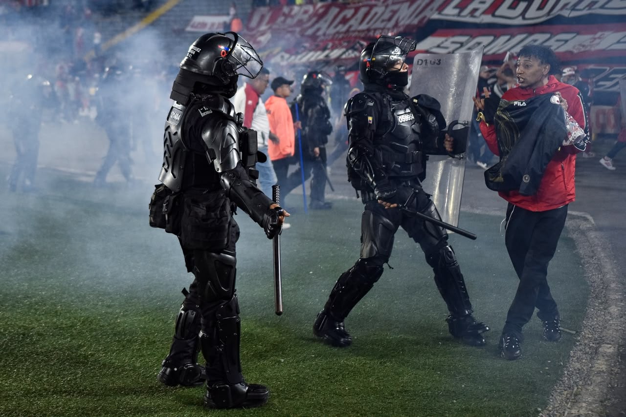 Momento en el que las unidades de seguridad retiran del campo de juego a los hinchas de Santa Fe tras los enfrentamiento con la barra del América.
