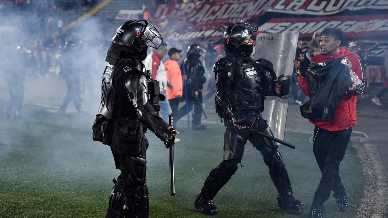 Momento en el que las unidades de seguridad retiran del campo de juego a los hinchas de Santa Fe tras los enfrentamiento con la barra del América.