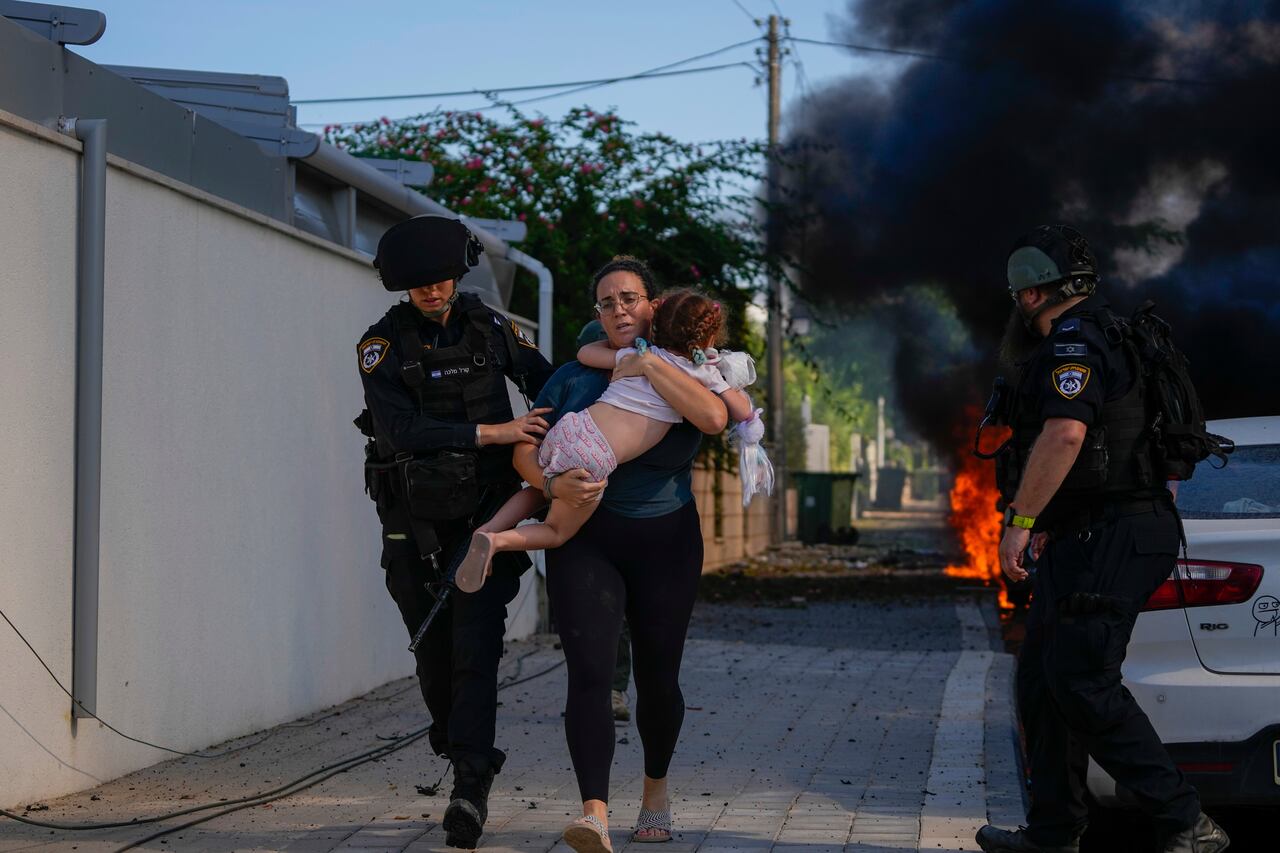 Policía israelí evacúa a una mujer y a un niño del sitio que fue impactado por un cohete en la franja de Gaza en Ashkelon, sur de Israel. (AP Photo/Tsafrir Abayov)