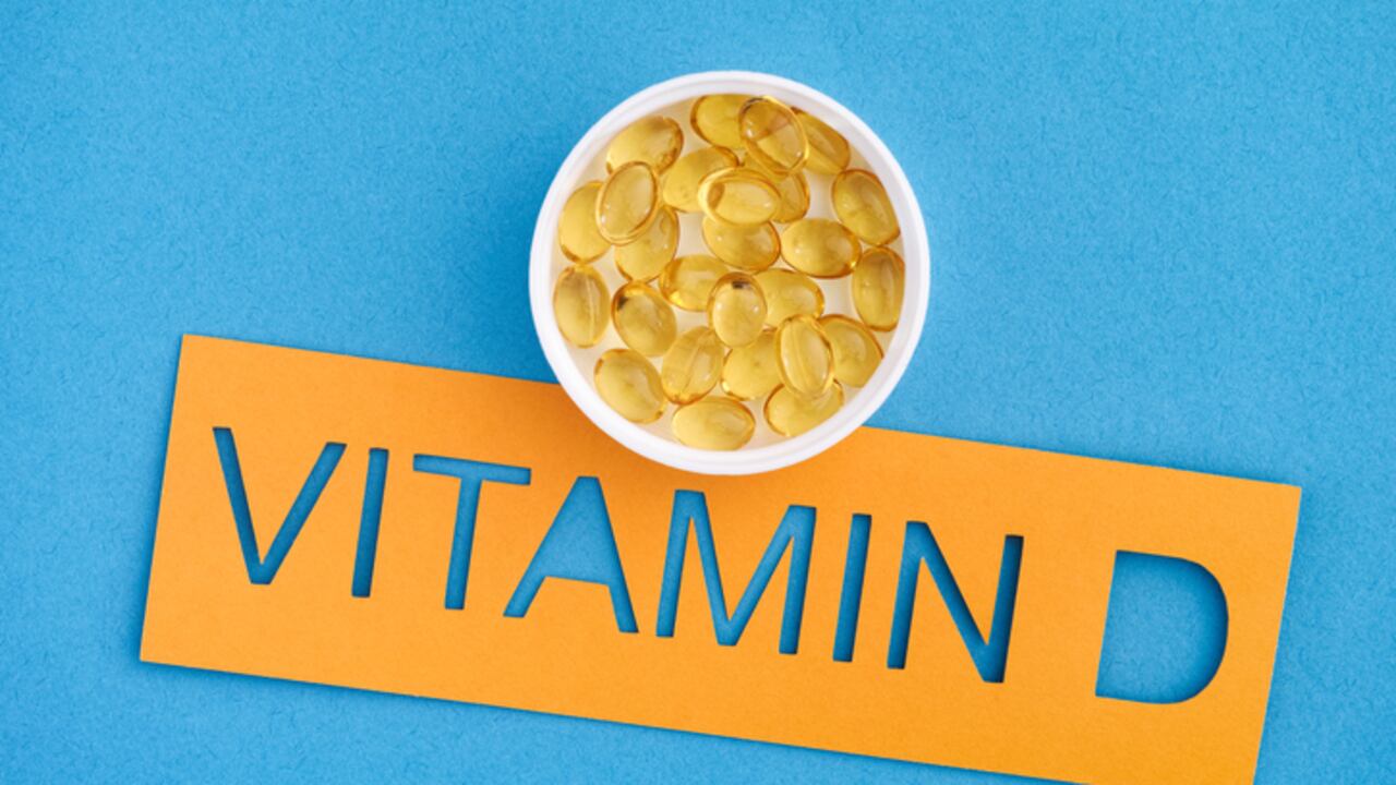 The word Vitamin D with a small cup of Vitamin D3 capsules on it. Close up.