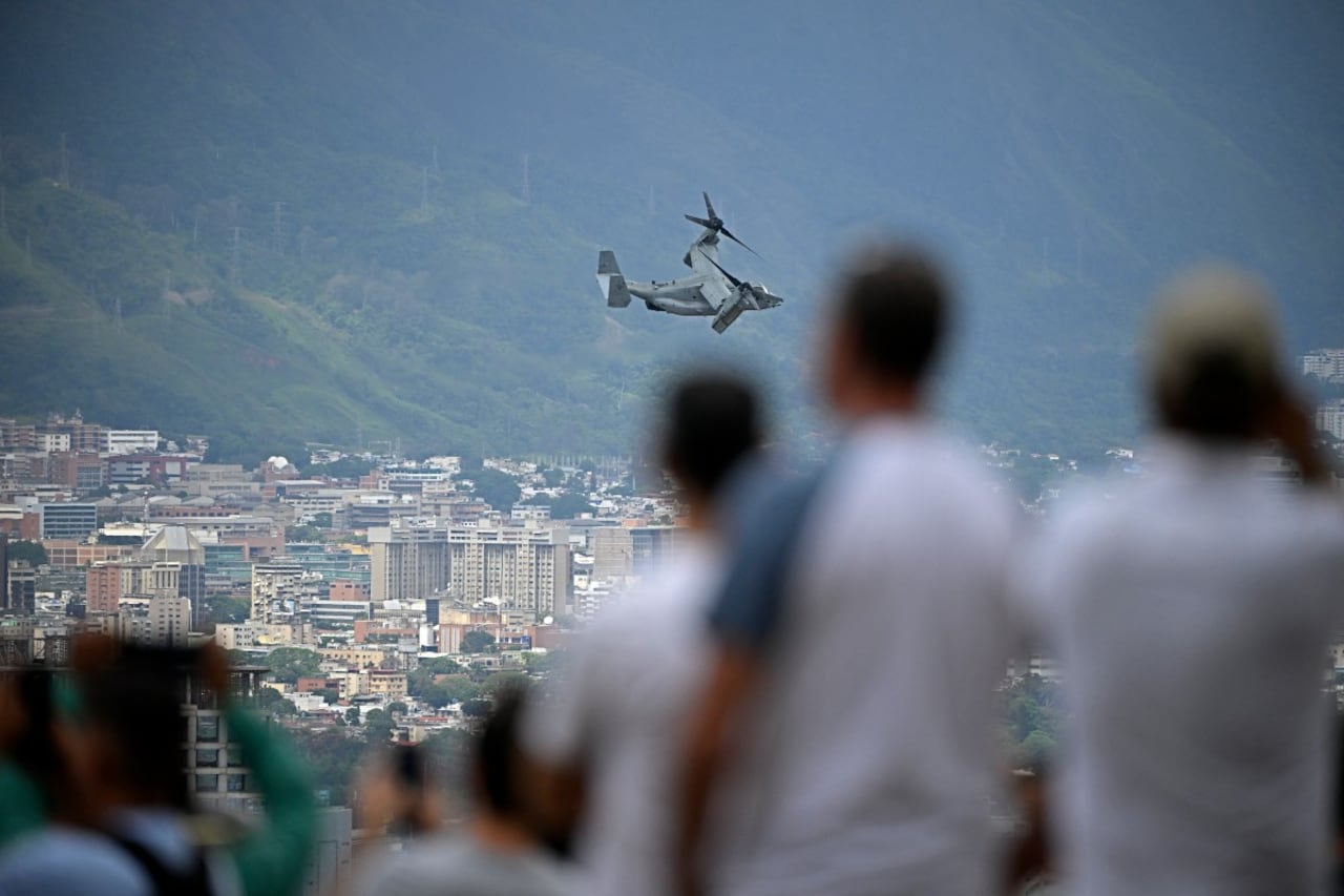 Varias personas observan un avión MV-22B Osprey de la Infantería de Marina estadounidense sobrevolando la ciudad en Caracas, camino a la Embajada de Estados Unidos