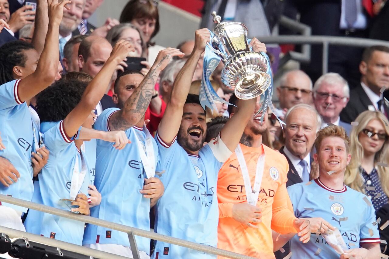 Ilkay Gundogan, del Manchester City, en el centro, sostiene el trofeo de los ganadores mientras celebra con sus compañeros ganar la final de la Copa FA inglesa entre el Manchester City y el Manchester United en el estadio de Wembley en Londres, el sábado 3 de junio de 2023. El Manchester City ganó 2-1 . (Foto AP/Dave Thompson)