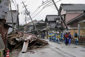 Police walk past collapsed houses hit by earthquakes in Suzu, Ishikawa prefecture, Japan Wednesday, Jan. 3, 2024. Rescue workers and canine units urgently sifted through rubble Wednesday ahead of predicted freezing cold and heavy rain in what the prime minister called a race against time after powerful earthquakes in western Japan killed multiple people. Dozens are believed trapped under collapsed buildings.(Kyodo News via AP)