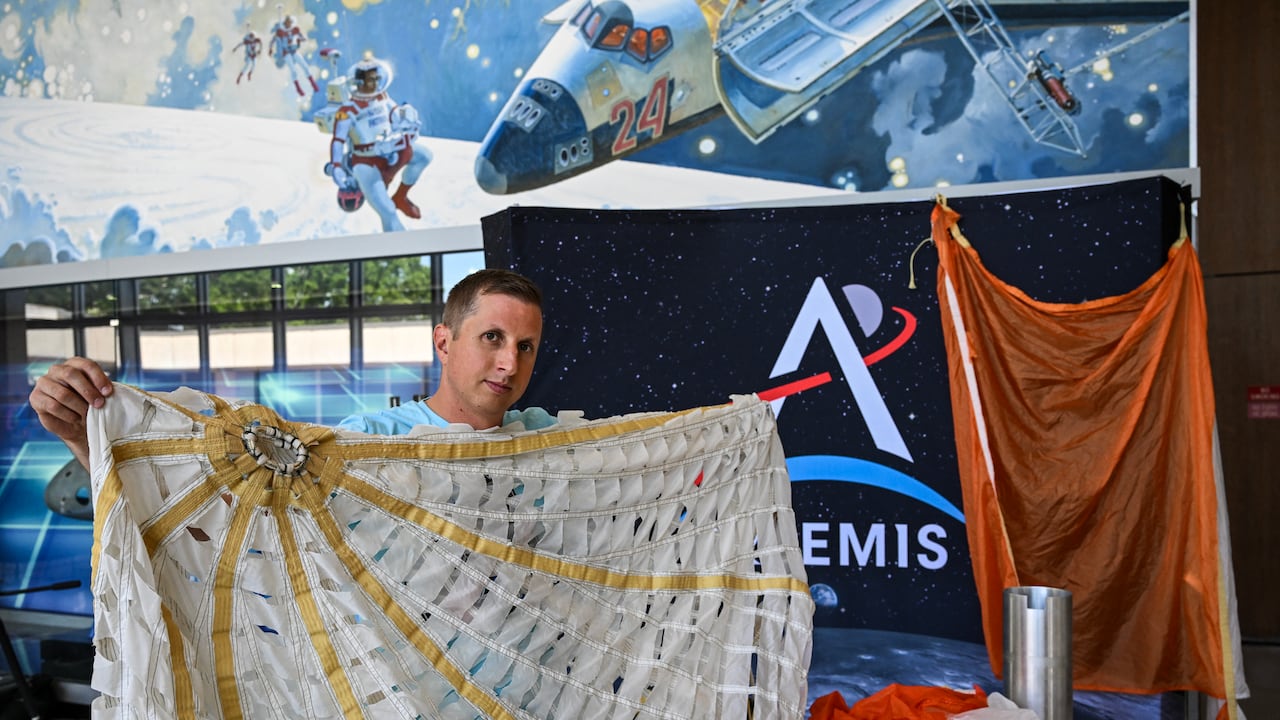 Jared Daum, ingeniero aeroespacial del Centro Espacial Johnson de la NASA, muestra el sistema de paracaídas de la nave espacial Orion