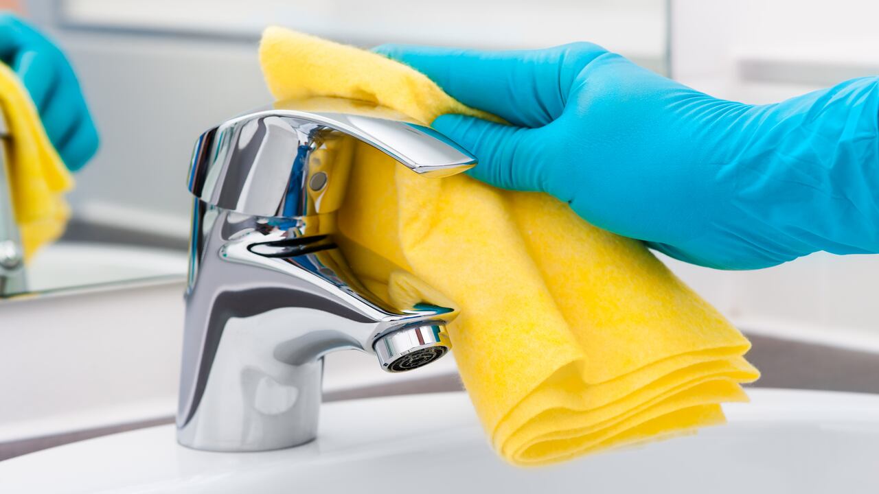 Woman doing chores in bathroom, cleaning tap