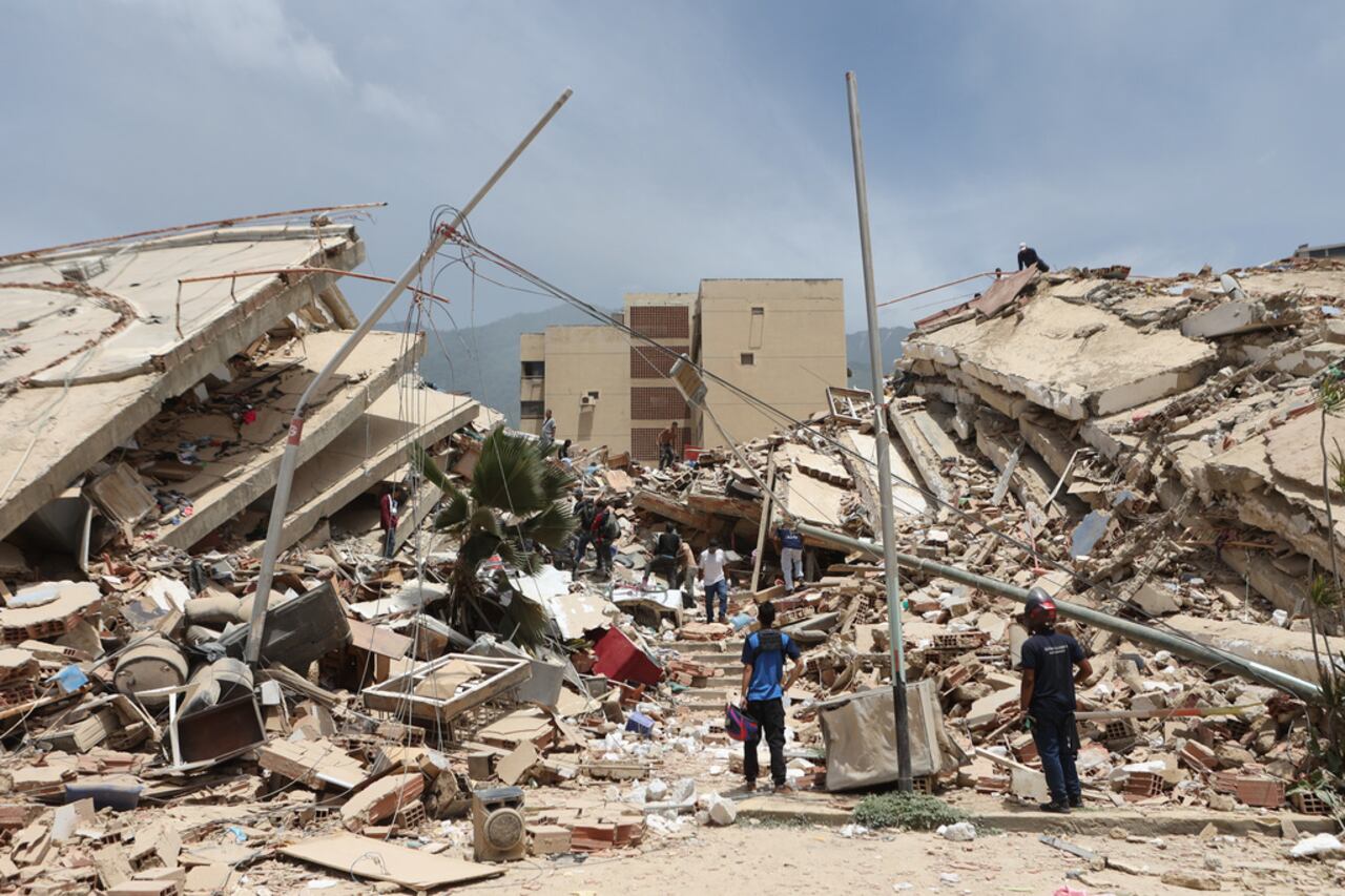 Residentes buscan entre los escombros de las casas dañadas durante un terremoto y varias réplicas que azotaron La Guaira, Venezuela, el jueves 25 de junio de 2026. (AP Foto/Pedro Mattey)