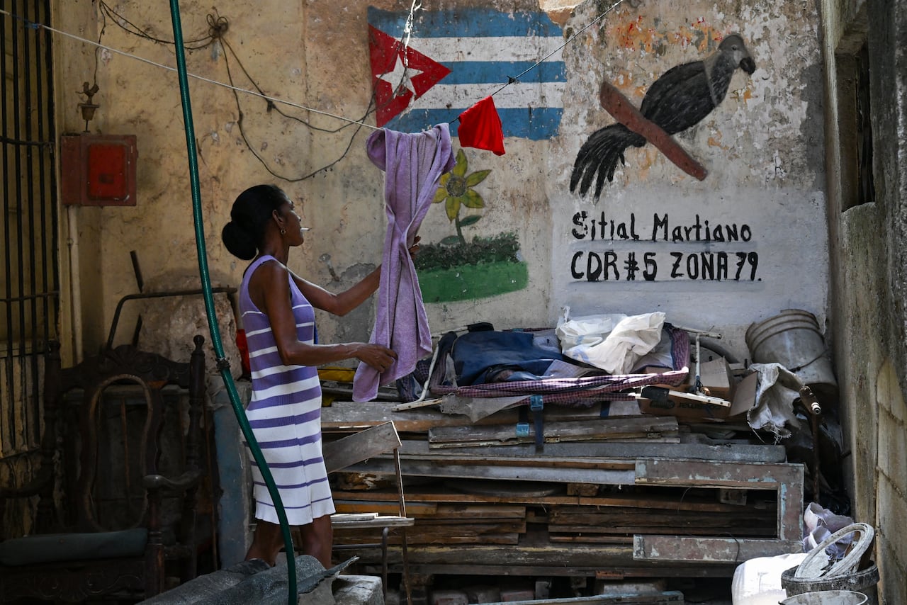 A woman takes a towel from her clothes line in a vacant lot in Havana on May 18, 2026. Cuba's leader warned on May 18 of a "bloodbath" in the event of an American attack, while the US Treasury sanctioned Cuba's main intelligence agency and top leaders as tensions spiked between the arch-foes. (Photo by YAMIL LAGE / AFP)