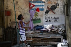 A woman takes a towel from her clothes line in a vacant lot in Havana on May 18, 2026. Cuba's leader warned on May 18 of a "bloodbath" in the event of an American attack, while the US Treasury sanctioned Cuba's main intelligence agency and top leaders as tensions spiked between the arch-foes. (Photo by YAMIL LAGE / AFP)