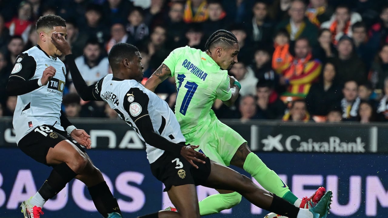 El delantero brasileño del Barcelona #11 Raphinha (R) controla el balón desafiado por el defensor español del Valencia #03 Cristhian Mosquera.