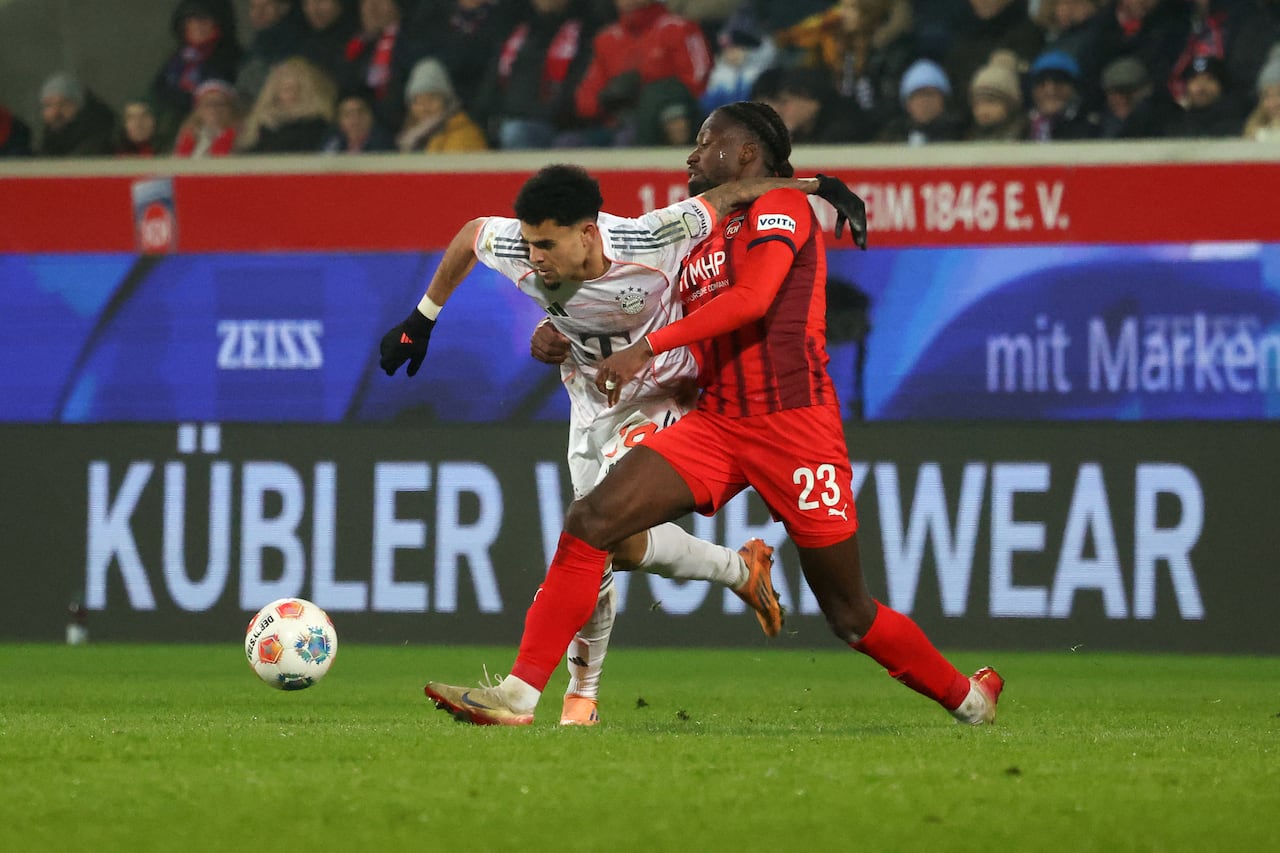 El defensa alemán #23 del Heidenheim, Omar Traore (R), y el delantero colombiano #14 del Bayern Munich, Luis Díaz, disputan el balón durante el partido de fútbol de la primera división alemana de la Bundesliga entre el FC Heidenheim y el FC Bayern Munich en Heidenheim, sur de Alemania, el 21 de diciembre de 2025. (Foto de Karl-Josef HILDENBRAND / AFP)